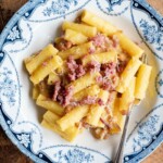 An overhead shot of potato, saffron and sausage pasta in a blue and white bowl.