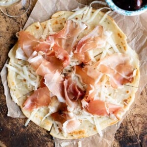 A close up cropped image of Brustengo, an Italian flatbread topped with meat and cheese.