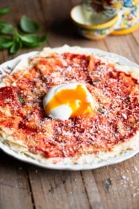 Pane Frattau on a plate (tomato and bread) topped with a poached egg.