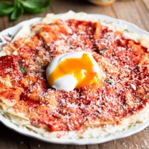 Pane Frattau on a plate (tomato and bread) topped with a poached egg.