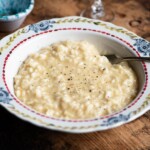 A close up cropped image of risotto alla Valdostana in a bowl ona. wooden surface.