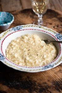 A bowl of cheesy Risotto alla valdostana sitting on a wooden board.
