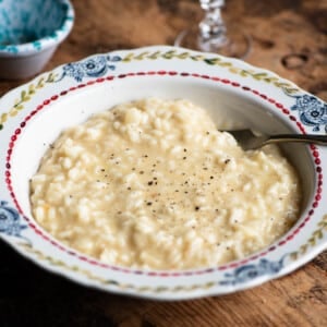A bowl of cheesy Risotto alla valdostana sitting on a wooden board.