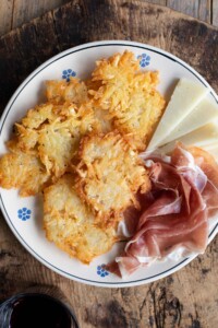 An overhead shot of Italian potato fritters on a plate with some cured meat and cheese.