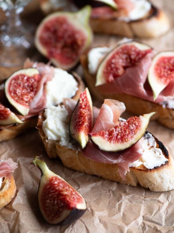 A close up of fig crostini with pecorino cream and prosciutto.