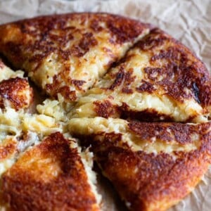 A close up of a cheesy potato cake cut into slices (frico).