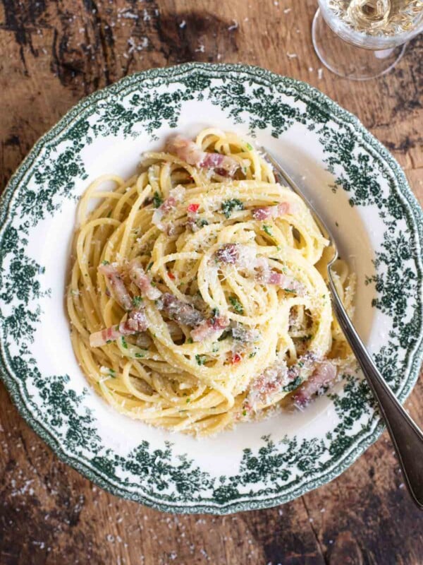 An overhead shot of spaghetti alla Molisana in a green patterned bowl on a wooden background.