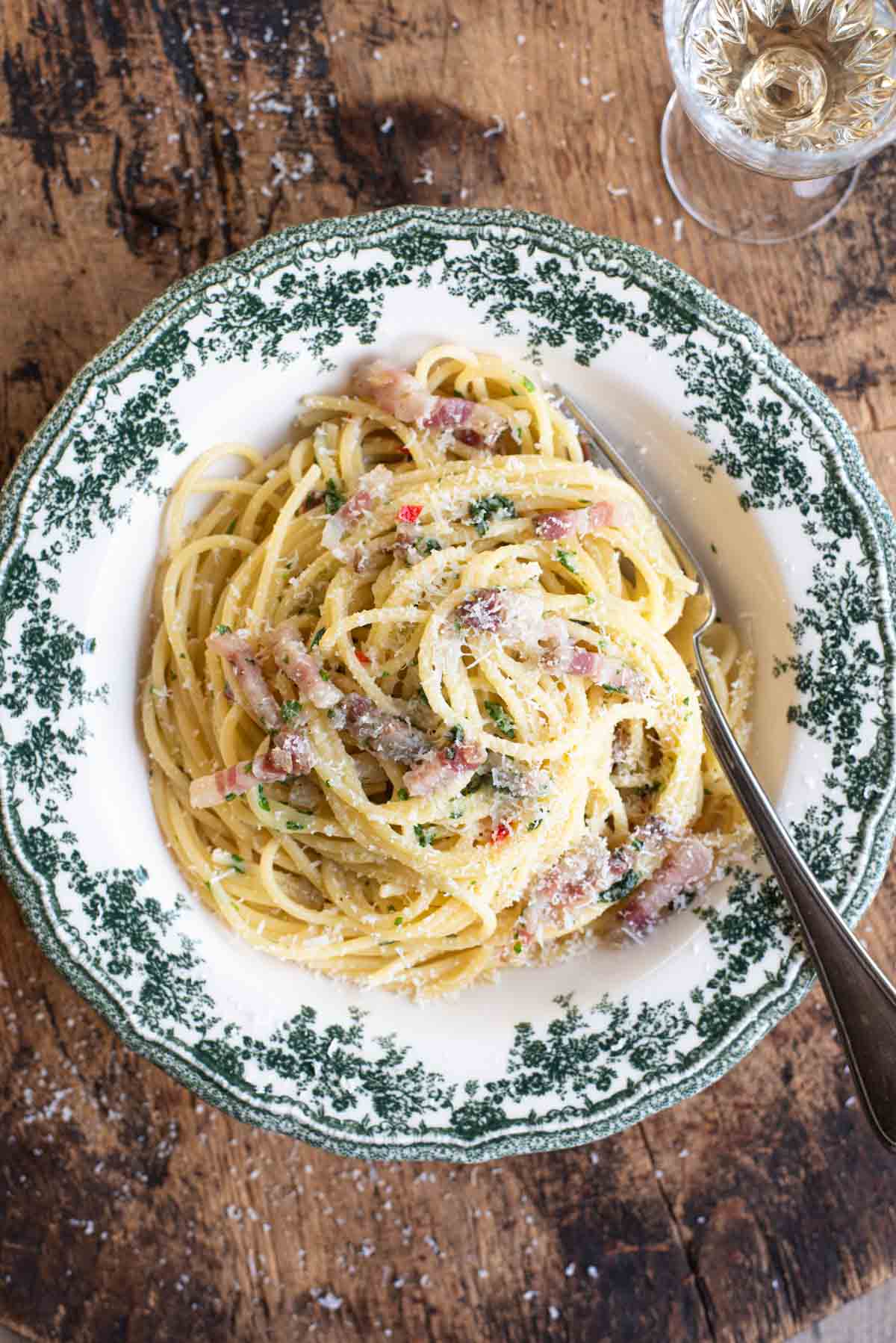 An overhead shot of spaghetti alla Molisana in a green patterned bowl on a wooden background.