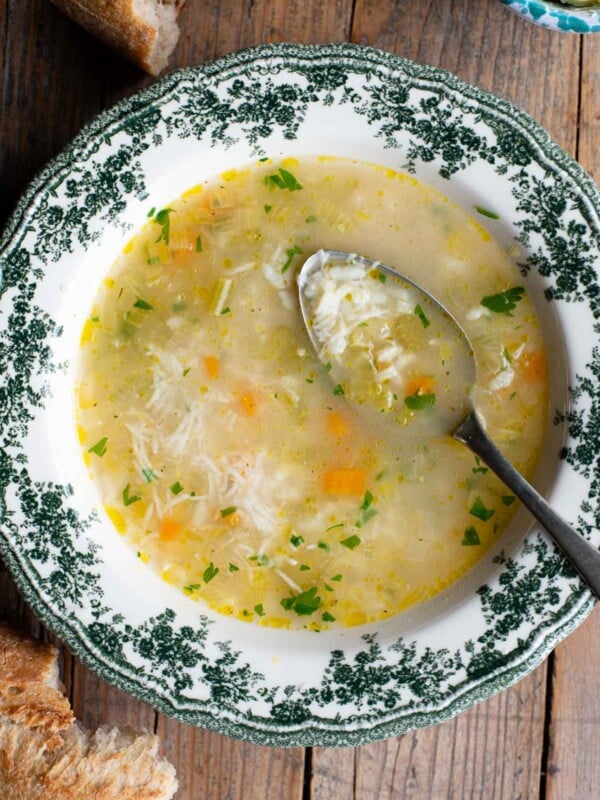 An overhead shot of an Italian rice soup in a green and white bowl with a spoon inside.