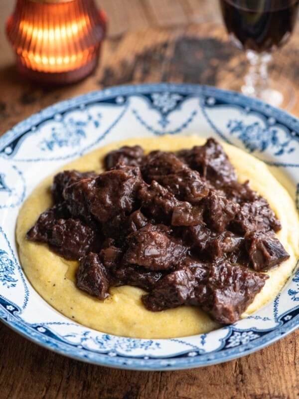 Carbonade beef stew served on top of polenta in a blue and white bowl.