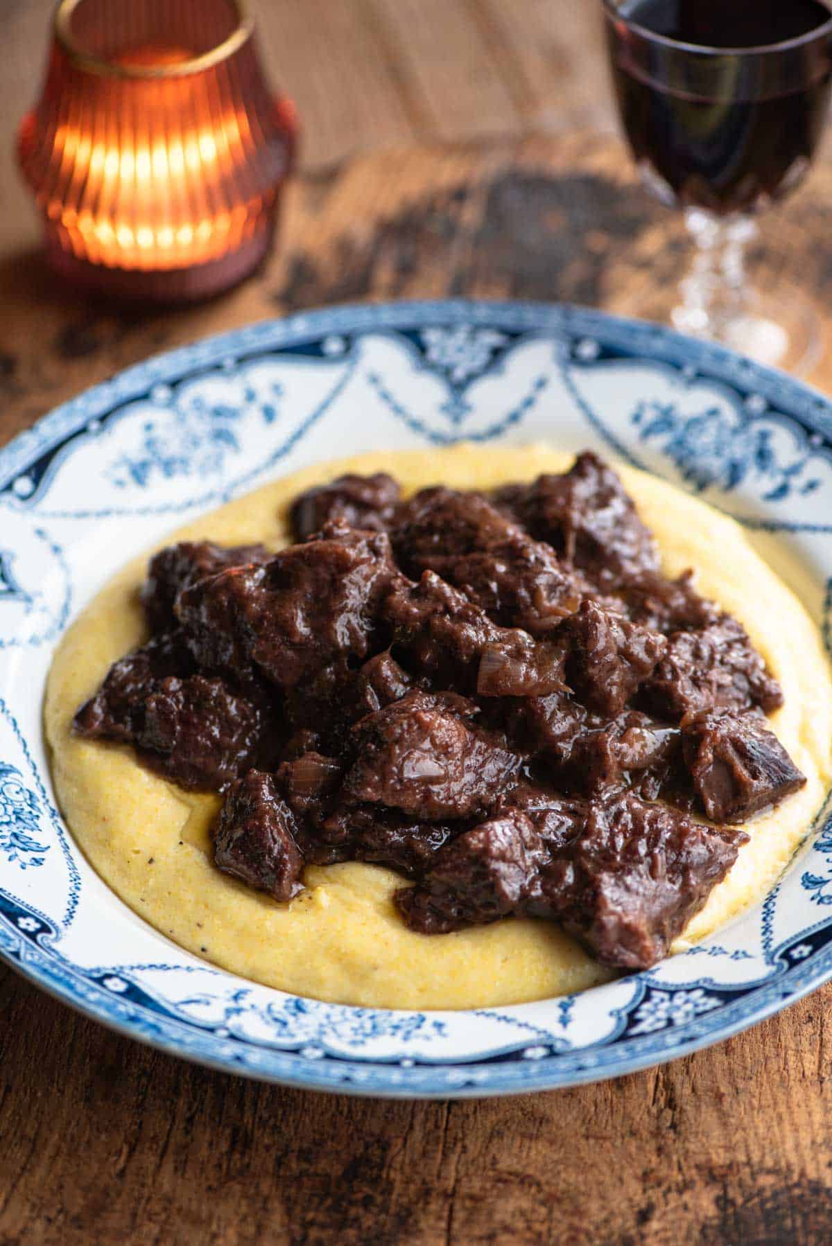 Carbonade beef stew served on top of polenta in a blue and white bowl.
