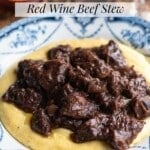 A close up of an Italian beef stew on top of polenta in a bowl.