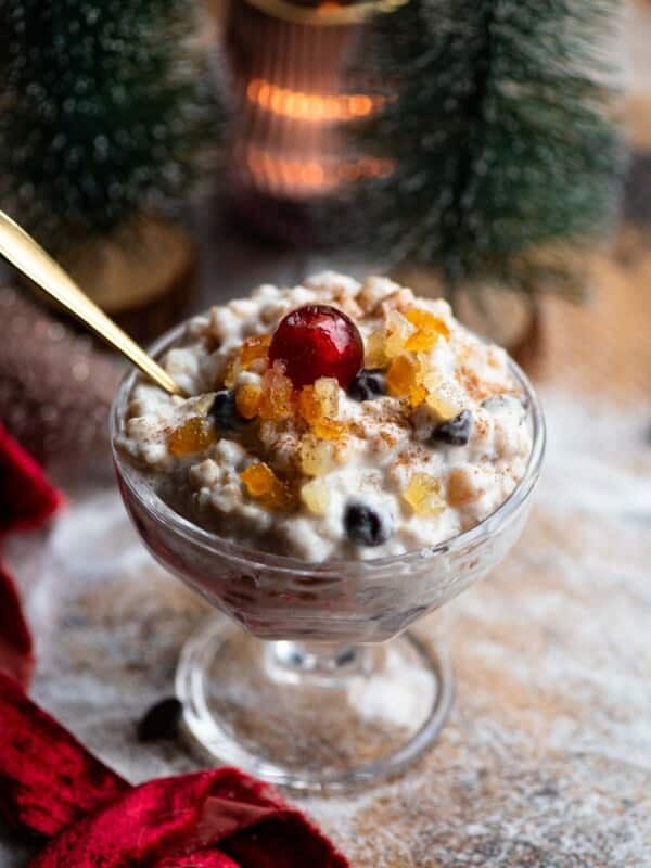 A Sicilian dessert made with ricotta, grain and candied fruit in a glass serving dish topped with a candied cherry.