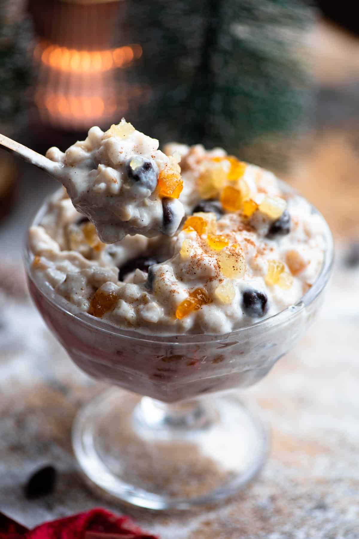 A spoon picking up a creamy ricotta grain dessert from a glass bowl.