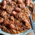 A cropped square image of Italian sausages and lentils on a serving plate.