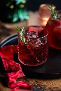 A red negroni sbagliato cocktail in a class with a sprig of rosemary.