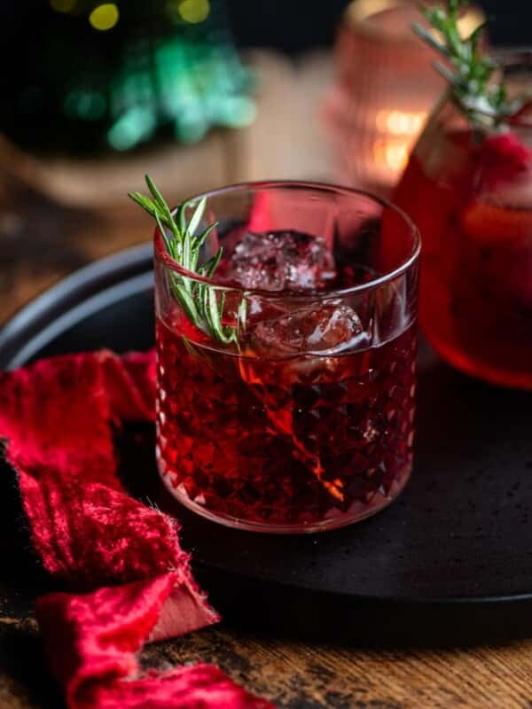 A red negroni sbagliato cocktail in a class with a sprig of rosemary.