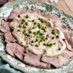 A cropped image of vitello tonnato on a serving platter.