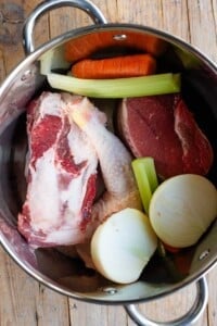 An overhead shot of meat and vegetables in a large stock pot.