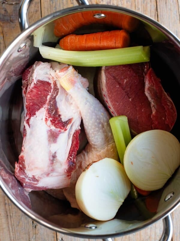 An overhead shot of meat and vegetables in a large stock pot.