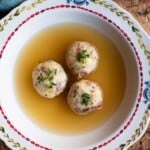 A cropped square image of Canederli dumplings in meat broth.