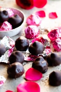 Homemade Italian baci chocolates on a travertine worktop with pink foil wrappers.