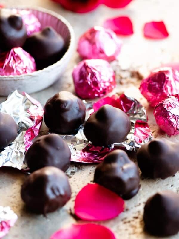 Homemade Italian baci chocolates on a travertine worktop with pink foil wrappers.