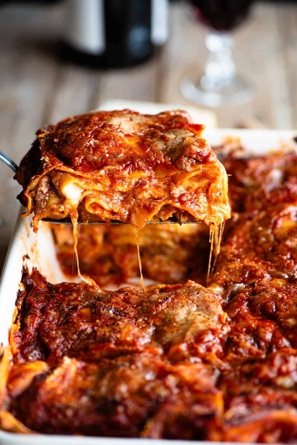 A side shot of a slice of neapolitan lasagna getting picked up from a dish.