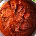 An overhead shot of Neopolitan ragu in a large pot on a wooden surface.