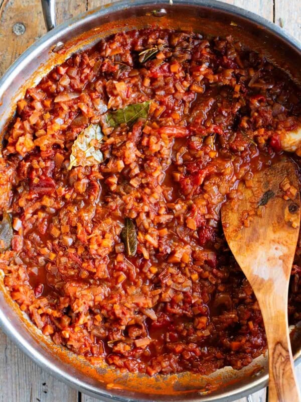 An overhead shot of a skillet with an Italian slow cooked vegetable sauce sitting on a wooden table.