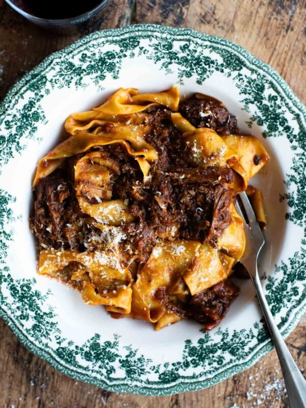 An overhead shot of a short rib beef ragu in a green and white bowl.