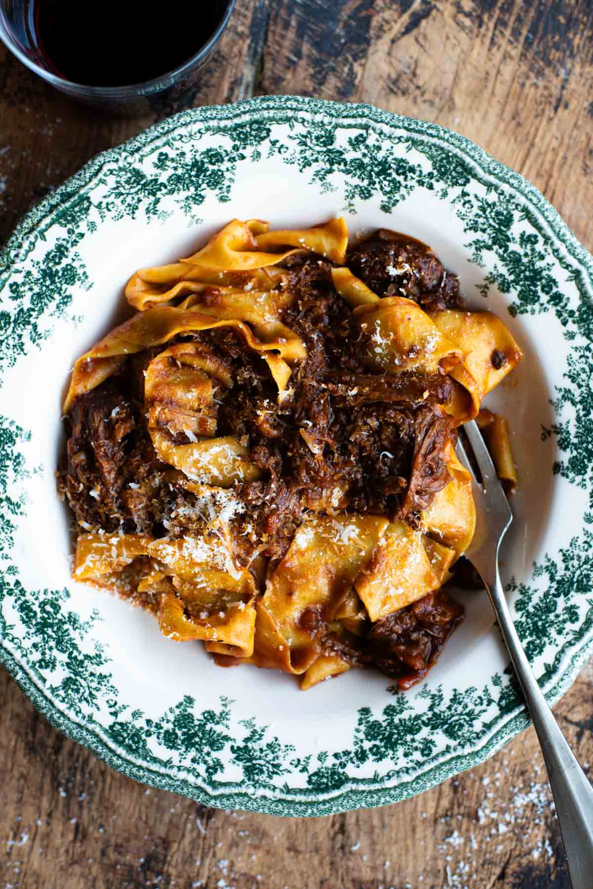 An overhead shot of a short rib beef ragu in a green and white bowl.