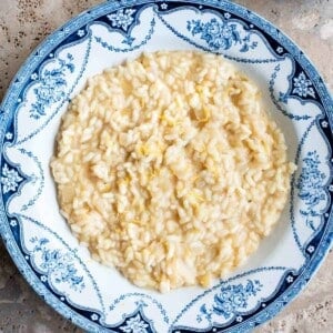 An overhead cropped image of lemon risotto in a blue and white bowl.