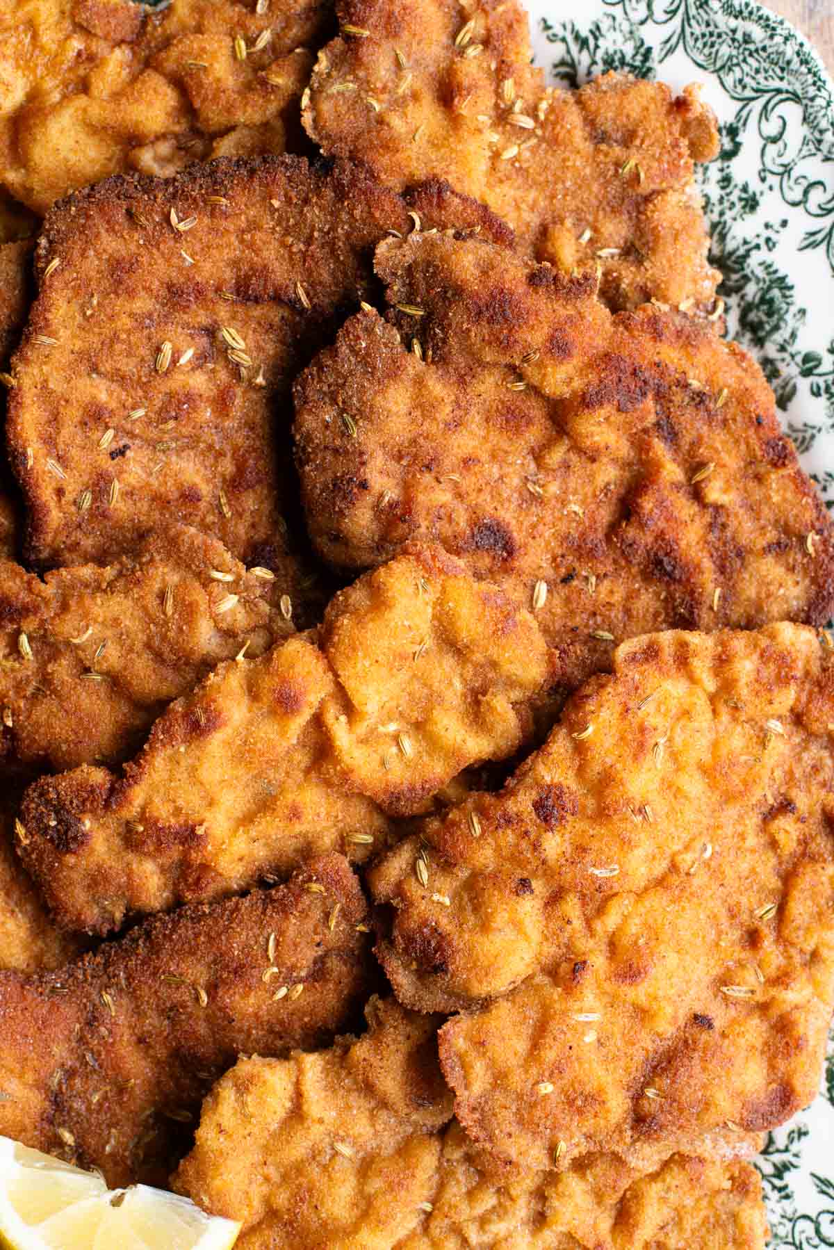 A close up of breaded pork fillet with fennel seeds on a plate.
