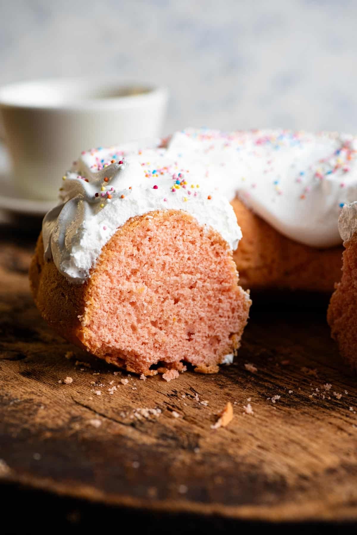 An Italian bundt cake cut open to reveal a bright pink sponge topped with meringue.