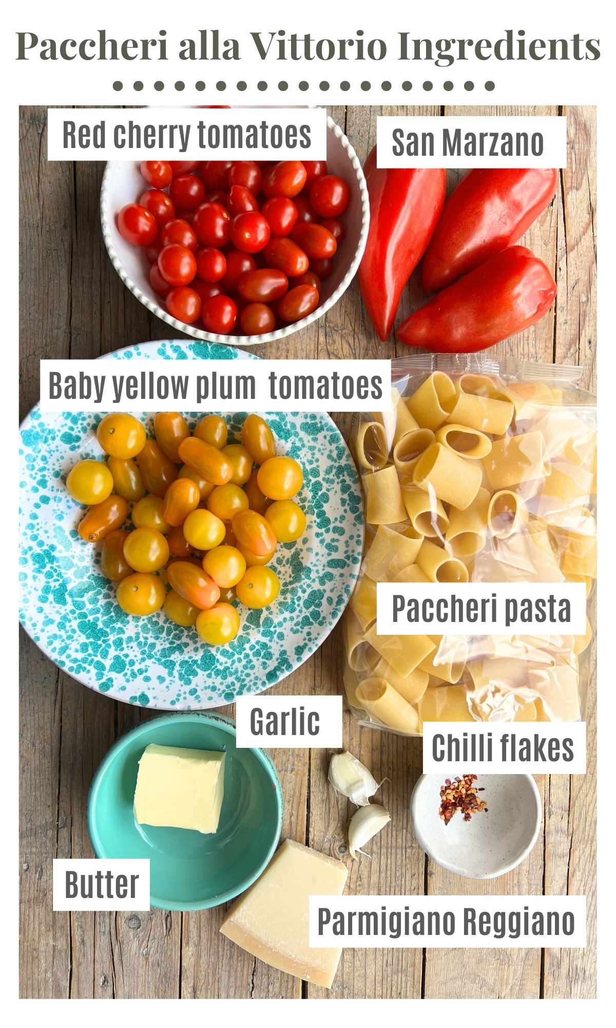 All the ingredients needed to make pasta alla vittorio on a wooden board; plum tomatoes, cherry tomatoes, butter, parmigiano reggiano, garlic, chilli flakes and paccheri pasta.
