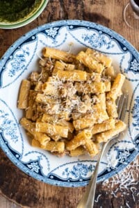 Pasta alla Montecarlo (creamy meat sauce) in a country style blue and white bowl sitting on a wooden chopping board.