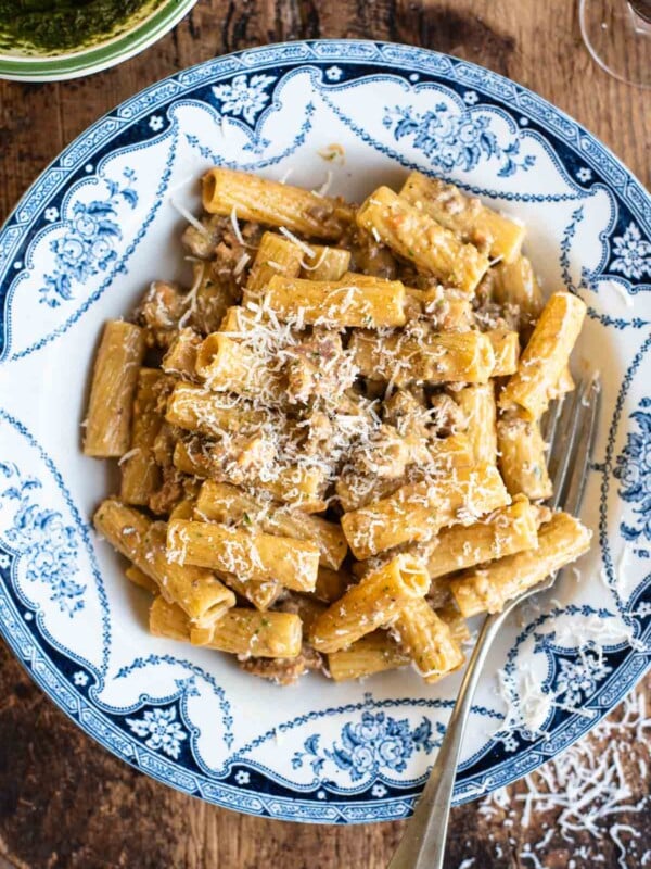 Pasta alla Montecarlo (creamy meat sauce) in a country style blue and white bowl sitting on a wooden chopping board.