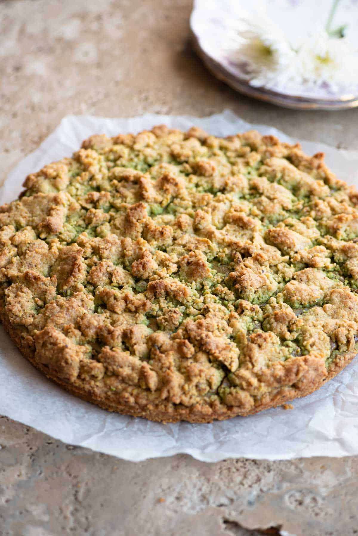 An Italian pistachio crumb cake sitting on a travertine surface.