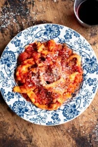 Trippa Finta (Italian omelette in tomato sauce) in a blue and white bowl sitting on a wooden surface.
