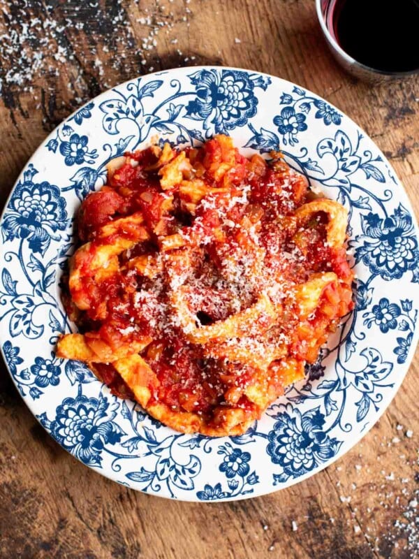 Trippa Finta (Italian omelette in tomato sauce) in a blue and white bowl sitting on a wooden surface.