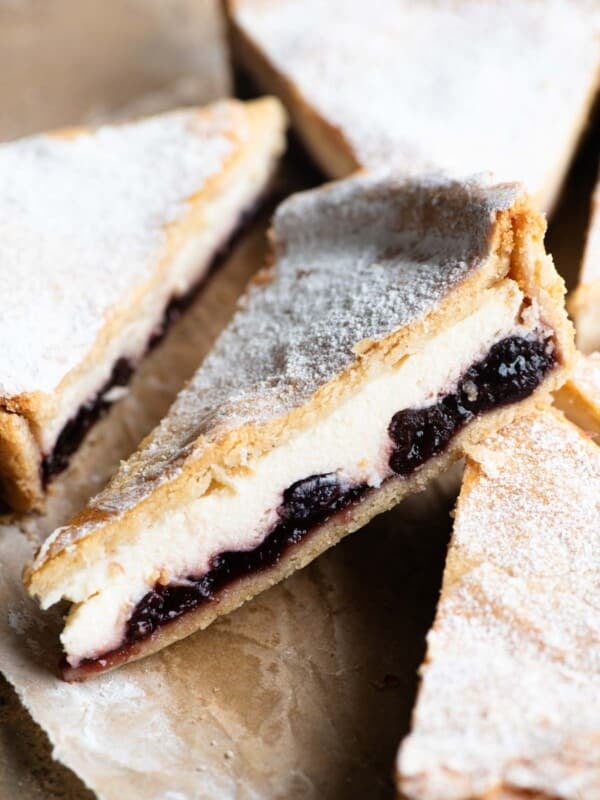 A close up of a slice of ricotta and cherry crostata dusted with powdered sugar.