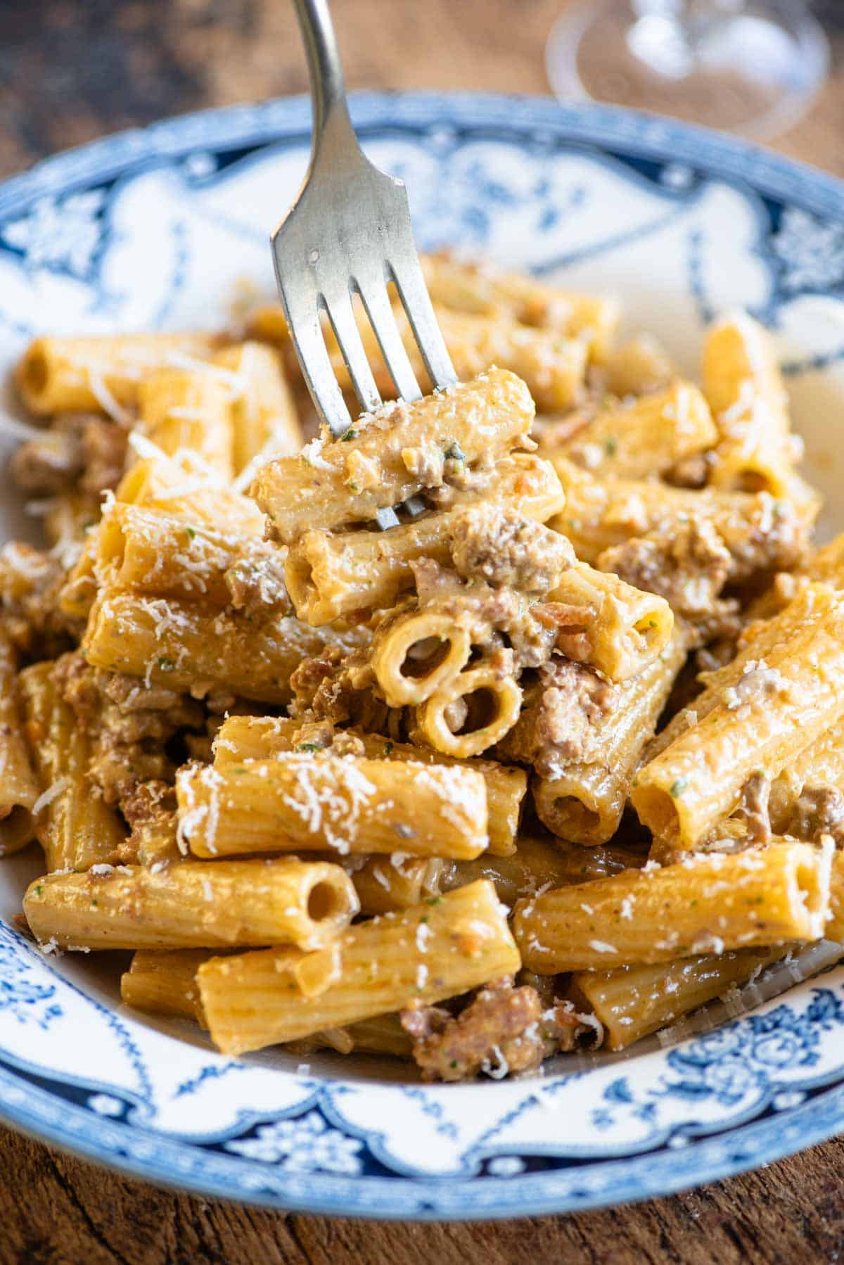 A close up of a fork picking up a bite of pasta in a creamy meat sauce.