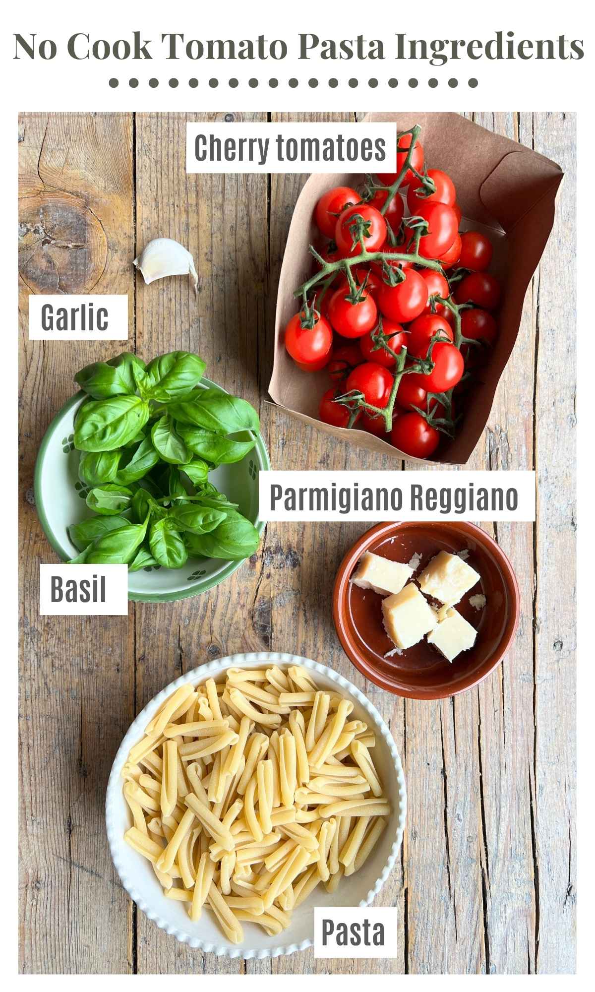 The ingredients needed to make a no cook tomato pasta laying on a rustic wooden surface; cherry tomatoes, pasta, garlic, Parmigiano Reggiano and basil.