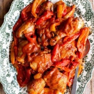 A close up of chicken and peppers on a green and white servings plate.