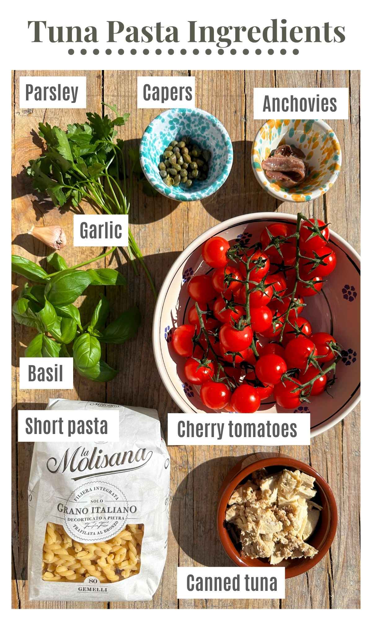 All the ingredients needed to make a tuna pasta sauce in bowls on a rustic wooden surface.