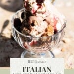 An Italian ice cream sundae served in a clear glass dessert bowl, topped with whipped cream, sour cherries, cocoa powder, and crumbled biscotti. The sundae is rich with chocolate and vanilla gelato. Text overlay reads “Italian Ice Cream Sundae – Authentic Recipe.
