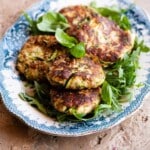 A cropped image of zucchini patties on a blue and white serving plate.