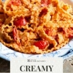 A close up of a creamy tomato pasta with sautéed cherry tomatoes on top. The text overlay reads: creamy tomato pasta - get the recipe.
