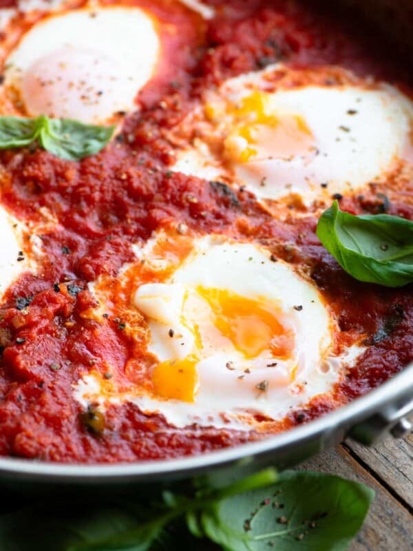 A close up of eggs in purgatory with a runny yolk in a pan.
